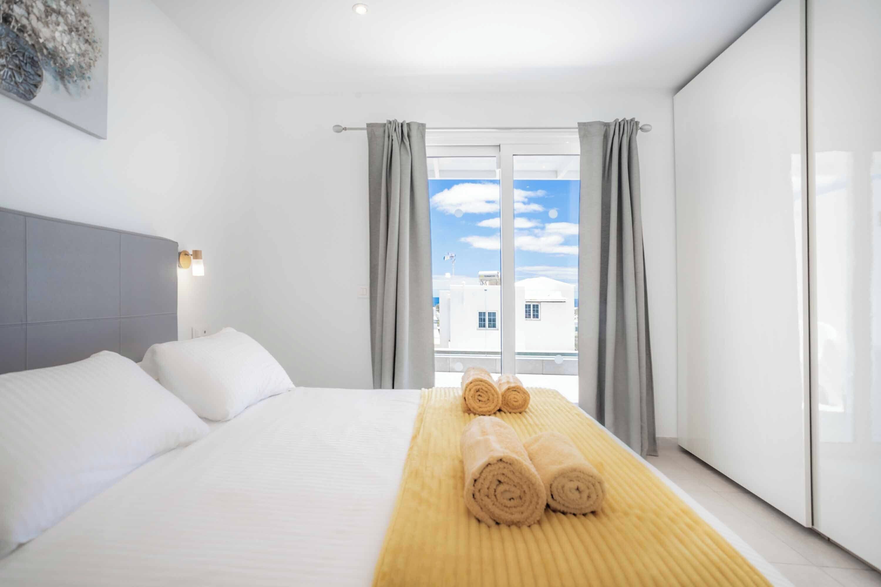 Hotelkamer met een groot bed, een hoofdbord, een raam met gordijnen en uitzicht op gebouwen.