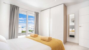 A modern hotel room with a large bed, a view of the city, and a sliding closet. - Villa Mi Deseo (Tías)