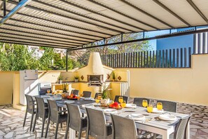 An outdoor patio with a covered dining area, a grill, and a refrigerator. - Villa Enzo Moraira (Teulada)