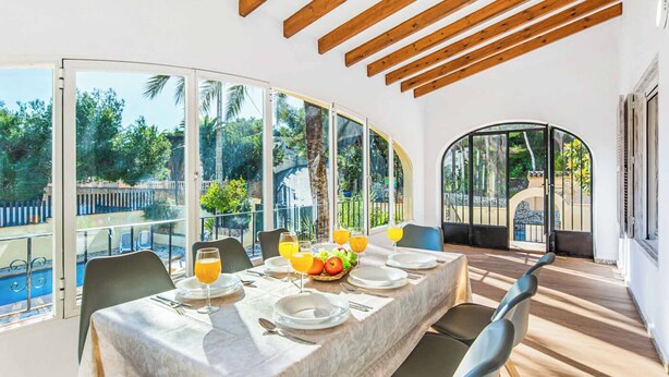 Un comedor con una mesa dispuesta para cuatro personas, ventanas amplias y vistas al exterior.
