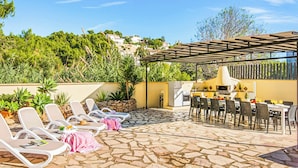 Un patio exterior con sillones de descanso, zona de comedor y una parrilla.