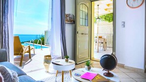 A room with a view of the sea, a door leading outside, a globe, and a table with a notebook and pen. - Villa Baby Lemoni (Kefalonia)