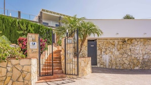 A gated entrance with a stone wall and a staircase leading to a building.