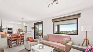 A modern living room with a sofa, coffee table, and dining area.