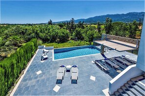 A rooftop pool area with lounge chairs and a view of the surrounding landscape.