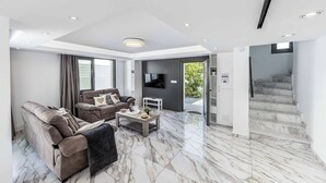 A modern living room with a sofa, coffee table, and TV. - Villa Christina Coral (Pegeia)