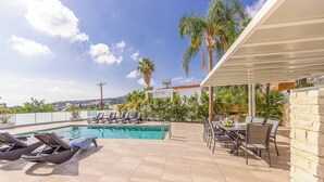 A rooftop pool area with lounge chairs and a dining table. - Villa Christina Coral (Pegeia)