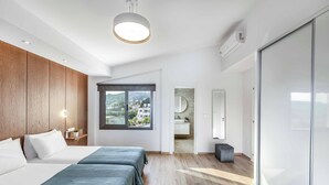 A modern hotel room with a large bed, a wooden panel wall, a large window, and a view of the outside. - Villa Christina Coral (Pegeia)