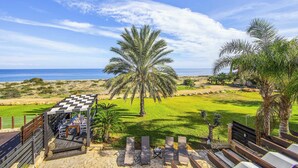 A terrace with a checkered roof, outdoor seating, and a view of the sea. - Villa El Greco (Paralimni)