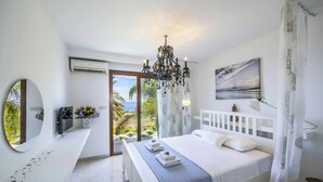 A bedroom with a bed, a chandelier, a TV, a mirror, and a painting. - Villa El Greco (Paralimni)