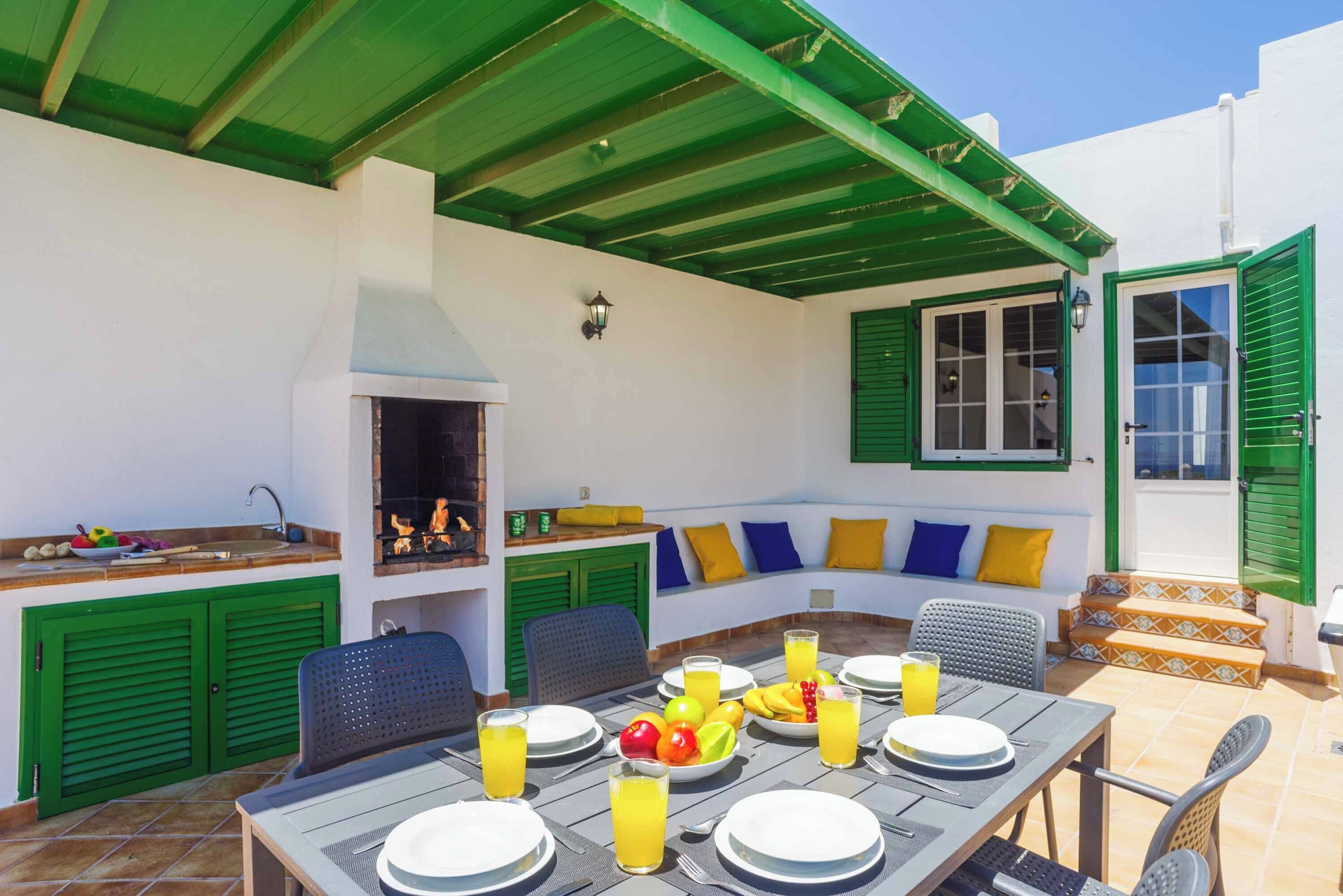 Een buiten eethoek met een barbecue, zitplaatsen en uitzicht op zee.