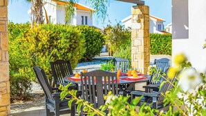 An outdoor patio with a round table, chairs, and a stone pillar. - Villa Eliza (Pegeia)