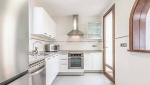 Una cocina moderna con armarios blancos, electrodomésticos de acero inoxidable y un horno empotrado.