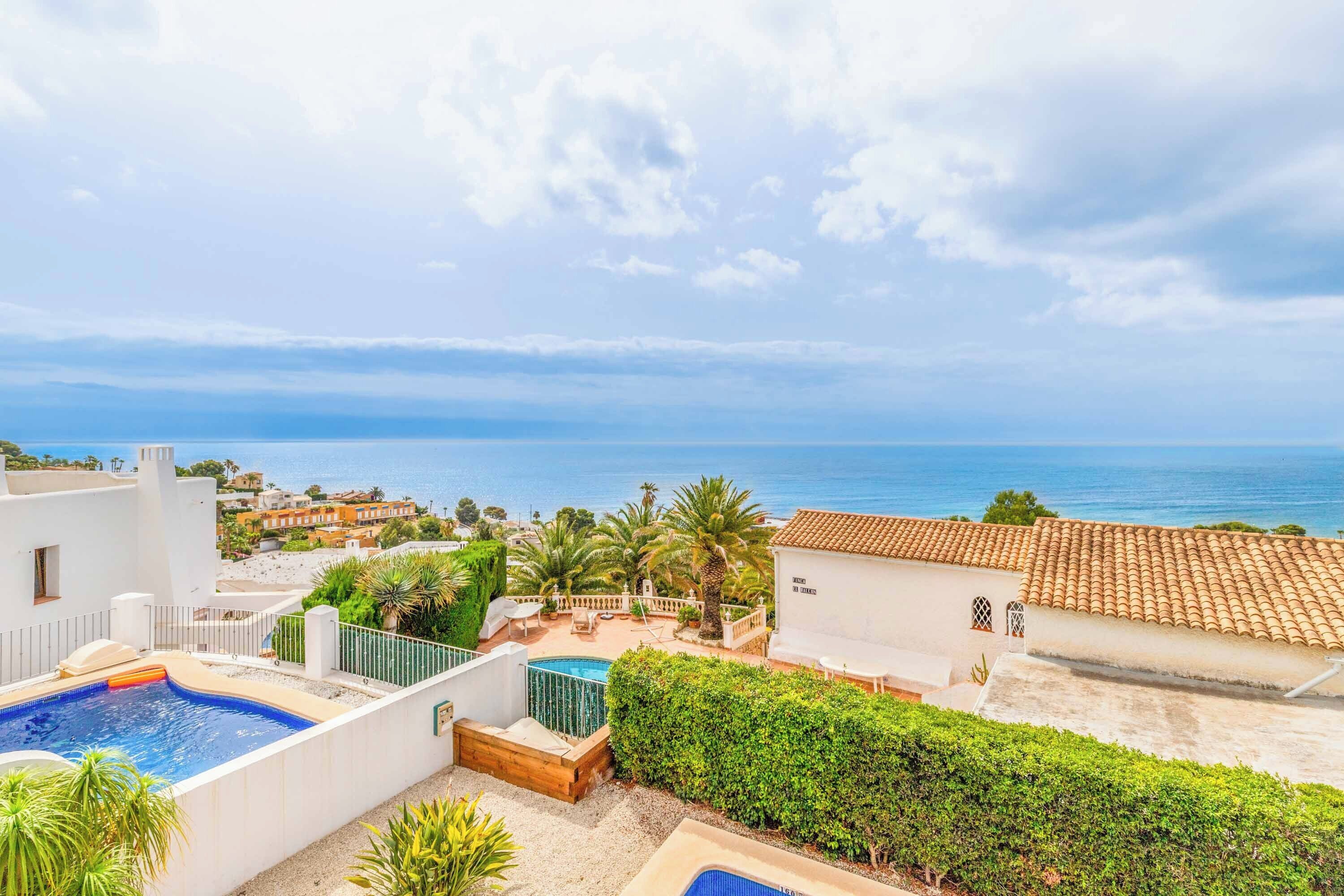 Zona de piscina en la azotea con vista al mar, rodeada de edificios y vegetación.