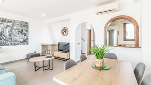 Una sala de estar moderna con una mesa de comedor, un televisor y un cuadro grande con una vista de la ciudad.