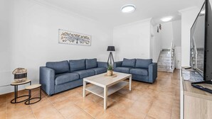 A modern living room with a grey sofa, a white coffee table, and a small side table with a lamp. - Villa Bonaci (Yaiza)