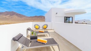 Una terraza en la azotea con dos sillones de descanso, una mesa y un pequeño espacio para sentarse.
