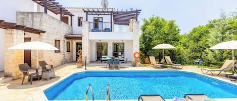A two-story building with a swimming pool, outdoor seating, and a pergola.