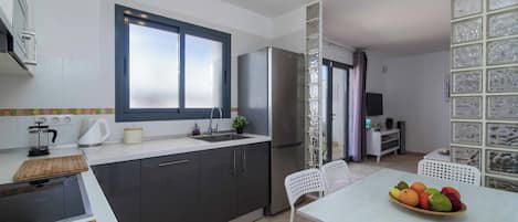 A modern kitchen with a built-in stove, a refrigerator, and a dining area with a table and chairs.
