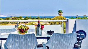 Ein Balkon mit Tisch für Zwei, einer Metallkanne und einer Weinflasche.