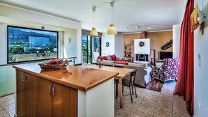 Eine moderne Küche mit einer großen Kochinsel, einem Essbereich und einem Wohnbereich mit einer Couch und einem Fernseher.