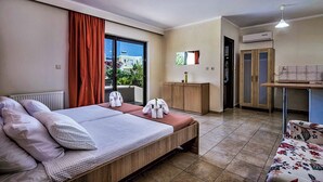 Ein Hotelzimmer mit Bett, kleinem Schreibtisch, Kleiderschrank und Blick ins Freie.