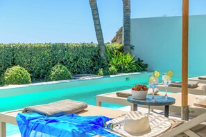 A poolside lounge area with a table set for two, a towel, and a hat.