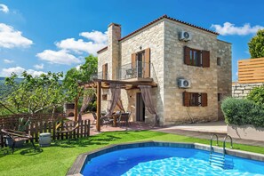 A stone building with a balcony, a swimming pool, and outdoor furniture. - Villa Erato Klio (Rethymno)