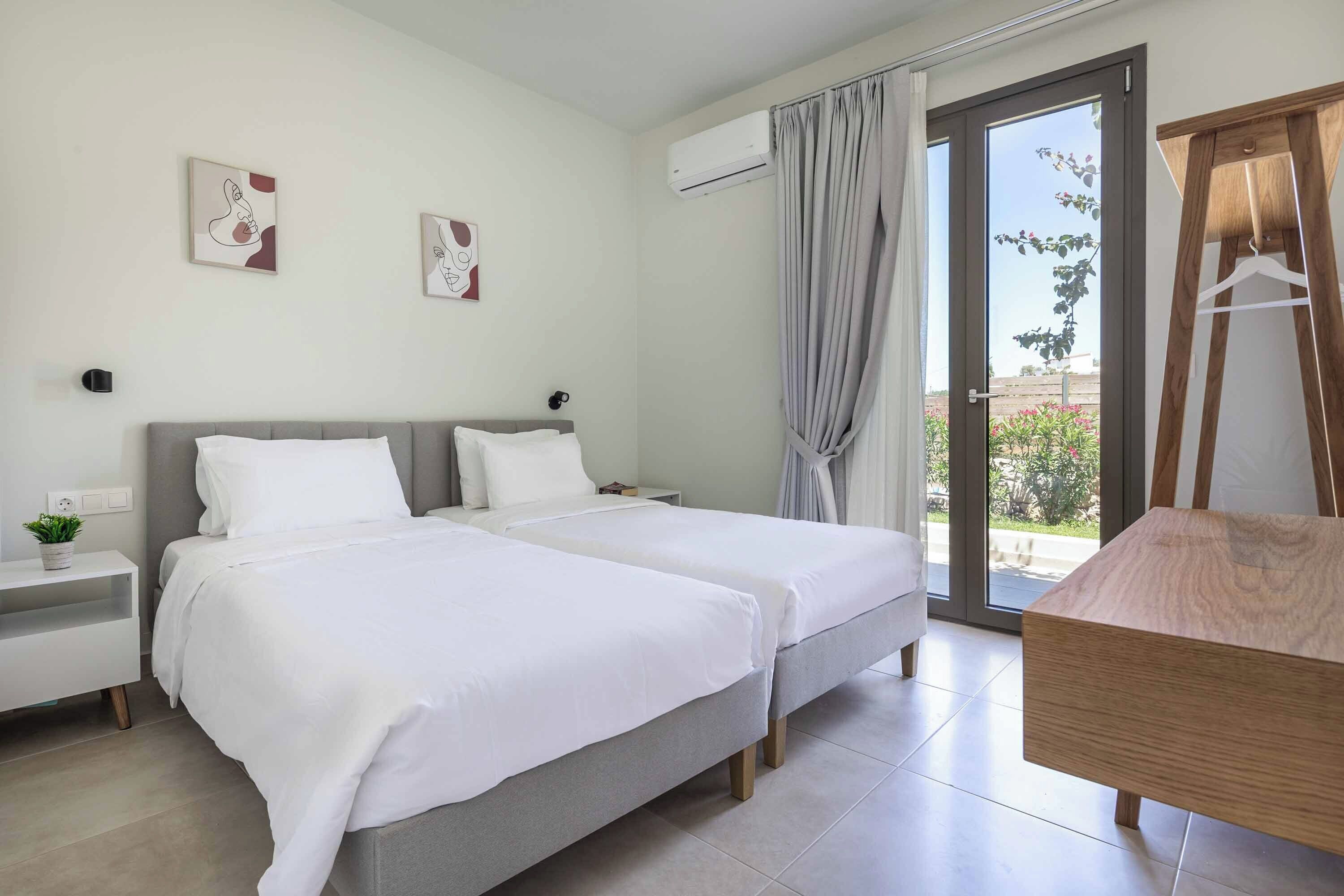 Une chambre d’hôtel moderne avec deux lits, une commode en bois et une grande fenêtre donnant sur l’extérieur.