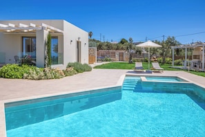 A modern outdoor pool area with a clear blue pool, a pergola, and lounge chairs. - Villa Kampos Ena (Rethymno)