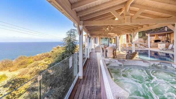 A wooden deck with a hot tub and lounge chairs overlooking a scenic view. - Pomos View (Pomos)