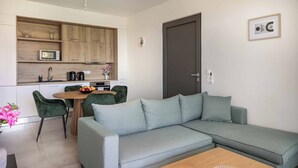 Una sala de estar moderna con un sofá seccional gris, una mesa de centro de madera y un comedor con una mesa redonda y sillas.