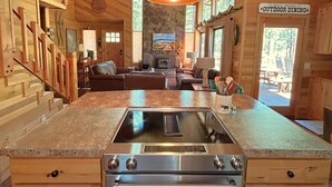 L’intérieur d’une cabane en bois comprend une cuisine équipée d’une cuisinière intégrée, un coin repas et un panneau indiquant un espace de restauration extérieur.