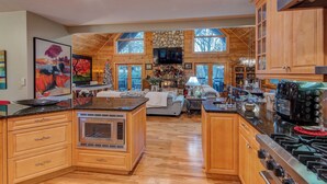 A spacious kitchen with wooden cabinets, a stone fireplace, and a large TV. - Blueberry Hills (Boone)