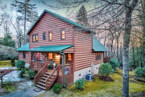 Une cabane en rondins avec un porche, un escalier et une petite terrasse.
