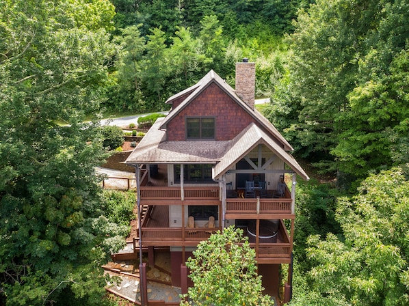 Ein zweistöckiges Holzhaus mit Balkon, umgeben von dichtem Wald.