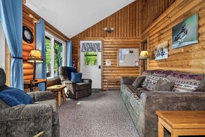 Et hyggeligt interiør i en træhytte med sofa, lænestol og et lille bord.