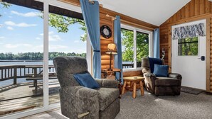 A cozy room with a large window, a clock, a lamp, and a view of a dock.