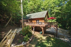 Une cabane en bois dotée d’une terrasse, entourée d’une forêt dense.