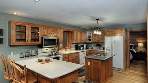 Eine Küche mit Holzschränken, einer Granit-Arbeitsplatte, einem Edelstahl-Kühlschrank und einem eingebauten Backofen.