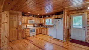 A wooden cabin with a kitchen featuring a microwave, stove, refrigerator, and sink. - Chestnut Lodge (Boone)