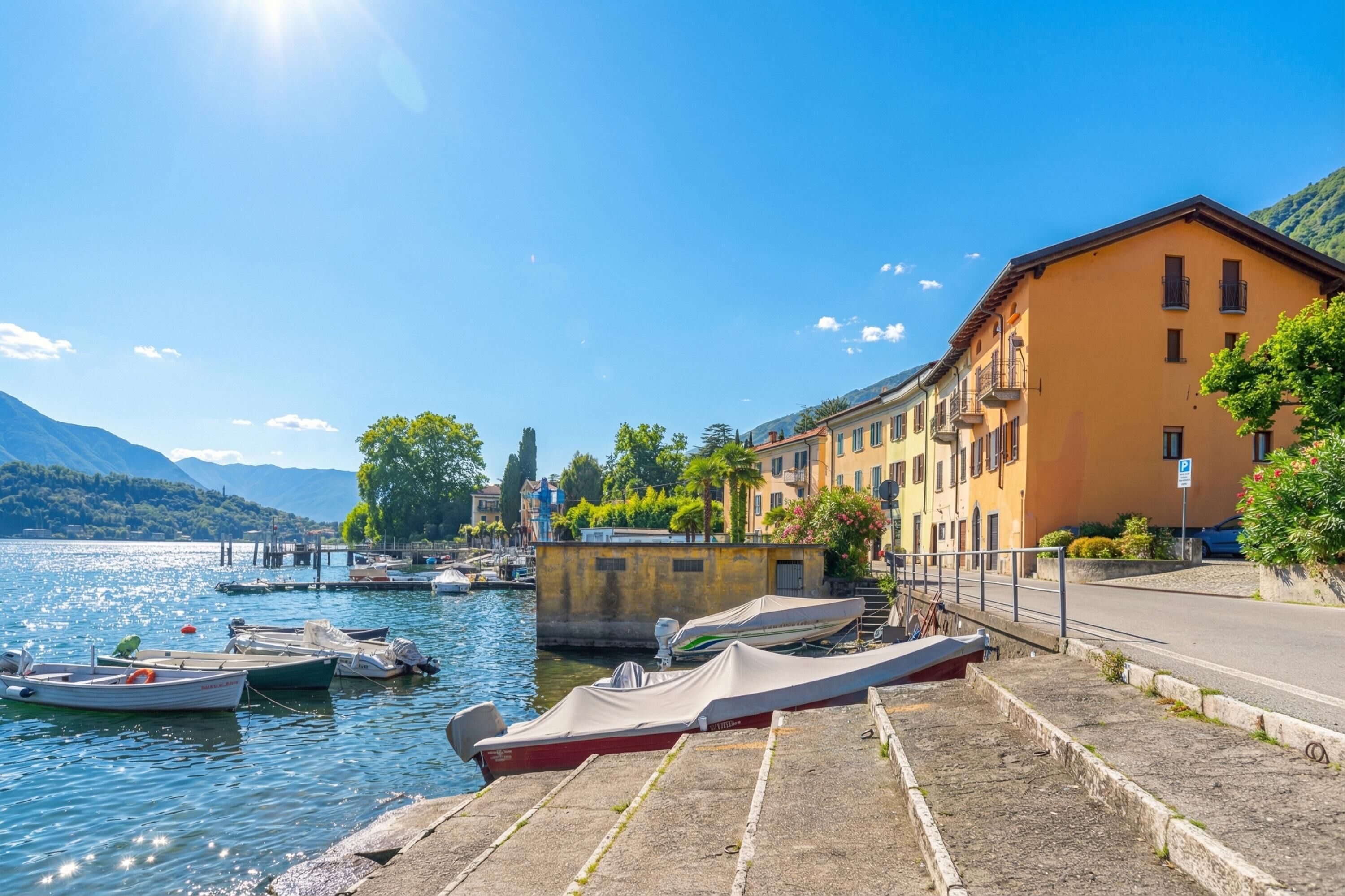 A waterfront hotel with boats docked, a paved walkway, and a mountain backdrop.