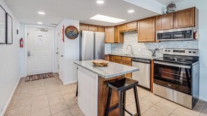 A modern kitchen with wooden cabinets, stainless steel appliances, and a central island. - Gulfstream Condos Unit 603 | Beautiful Gulf Views | Pool, Hot Tub, BBQ (Corpus Christi)