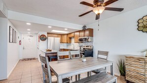 A modern kitchen with wooden cabinets, a dining table, and a ceiling fan. - Gulfstream Condos Unit 603 | Beautiful Gulf Views | Pool, Hot Tub, BBQ (Corpus Christi)