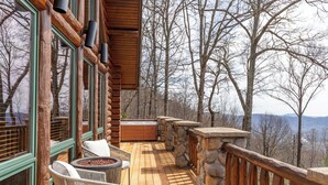 Une terrasse en bois avec des rampes en pierre, des chaises en osier et un jacuzzi.
