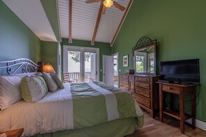 A bedroom with a bed, dresser, TV, and a balcony door. - Echota Ridge Boulders (Banner Elk)