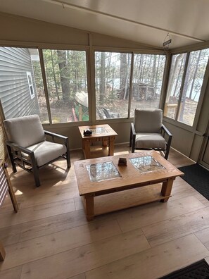 A sunroom with two chairs, a coffee table, and large windows overlooking a wooded area. - The Resting Place on Lake Louise (Johannesburg)