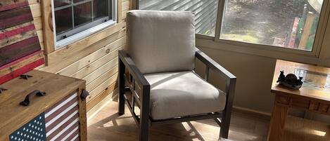 A wooden interior with a window, a cushioned chair, a table, and a flag-themed table.