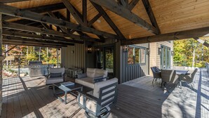 An outdoor deck with a grill, seating area, and a view of autumn foliage. - Ambience Lodge at Eagles Nest (Banner Elk)