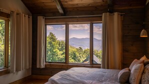 A bedroom with a large window offering a view of a mountainous landscape. - Ambience Lodge at Eagles Nest (Banner Elk)